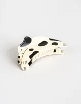 Broche para el pelo con forma de perro de color crema con manchas negras.