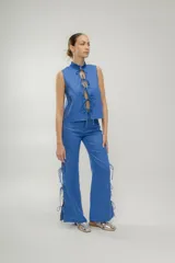 Pantalón de lino azul con aberturas laterales y lazos ajustables.