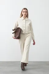 Pantalón de mujer color beige claro, tiro medio/alto, con corte flare (acampanado) y pespuntes a contratono.