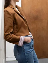 Blazer crop color marrón, marca Dictionary. Cuello con solapa, manga larga y forro interno estampado a rayas.