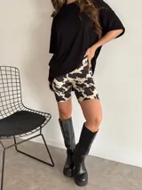 Conjunto de remera negra oversize y biker estampada con manchas color crema y negro.