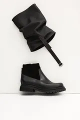 Bota de caña media color negro, con hebilla lateral y suela track.