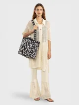 Bolso térmico (cooler bag) de gran tamaño, color marrón rojizo, con estampado mixto de leopardo y cebra. Posee manija superior y correa ajustable para hombro, ambas de cinta blanca con estampado negro de monograma.