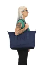 Bolso tipo tote de tela color azul marino con cierre superior y bolsillo frontal con fuelle. Tiene doble asa de mano y logo de la marca en el frente.