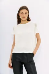 Remera blanca de lino con mangas cortas y calce al cuerpo. Presenta cadenas de strass en los hombros.
