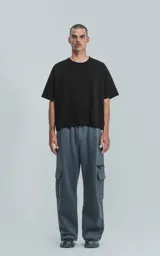 Pantalón de jogging gris oscuro, de corte amplio, con cintura y puños elásticos, bolsillos laterales y trasero, y bolsillo lateral adicional con cierre.