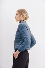 Campera azul de nylon con relleno de pluma, corte holgado a la cintura, cuello redondo y cierre frontal. Tiene bolsillos con cierre y detalle de vivos.