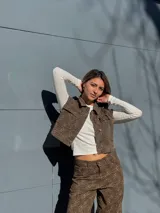 Chaleco corto con estampado animal print marrón y negro, cuello camisero, cierre frontal con botones y bolsillos de parche en el pecho.