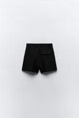 Bermudas negras de tiro alto con bolsillos delanteros, pinzas delanteras y cierre frontal con cremallera y ganchos metálicos.