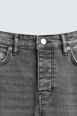 Pantalón de jean azul oscuro con efecto lavado y roturas en las rodillas, de corte ajustado al cuerpo desde la cintura hasta el tobillo.
