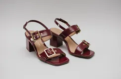 Sandalias de charol color borgoña con taco cuadrado y hebillas doradas.