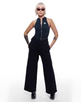 Pantalón de denim negro con corte sastrero de pierna ancha, tiro alto y pretina cruzada. Presenta un aplique de caballo/dragón en bronce hecho a mano y bordado del logo Temblad en la parte trasera.