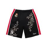 Short deportivo negro con cintura elástica, rayas rojas en los laterales y bordados florales en blanco. Presenta el logo de Supreme bordado en la parte inferior y un escudo con una corona y la letra S en la parte superior.