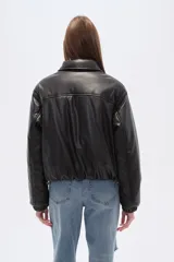 Campera estilo bomber de eco-cuero negra, con cuello camisero, cierre frontal y puños y cintura ajustados con elástico.