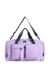 Bolso deportivo tipo duffle bag, color lila/lavanda, con múltiples bolsillos frontales con cierre y asas de mano negras. Incluye correa ajustable y desmontable para llevar al hombro.