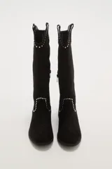 Botas texanas negras de caña media, confeccionadas en gamuza. Presentan un diseño de estilo western con detalles de tachas metálicas plateadas decorando el borde superior y el contorno del empeine. Tienen un taco bajo y punta ligeramente afilada.