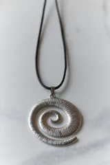 Collar con dije plateado en forma de espiral y cordón negro encerado.