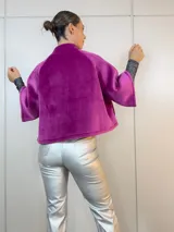 Chaqueta corta fucsia de terciopelo con cuello alto, mangas 3/4 amplias y cierre frontal con botones.