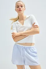Short de popelina de algodón a rayas verticales celestes y blancas. Tiene cintura elástica con cordón ajustable, bolsillos laterales y aberturas laterales cortas en el bajo.