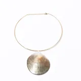 Collar rígido dorado con dije de ostra grande con reflejos nacarados.