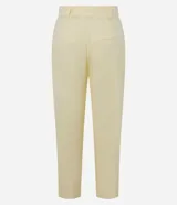 Pantalón zanahoria de cintura alta color amarillo pastel, confeccionado en viscolino con 15% de lino, con trabillas en la cintura, solapas con botón abajo de la cintura, pliegues y cierre tradicional.