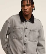 Campera trucker boxy de jeans gris con cuello de terciopelo negro, abotonada al frente, con bolsillos delanteros y mangas largas ajustadas.