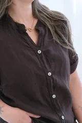 Camisa marrón de lino con cuello mao, cierre frontal con botones y mangas cortas con trabillas.
