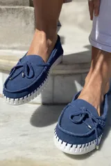 Mocasines náuticos azules de cuero con cordones decorativos y suela blanca de goma.
