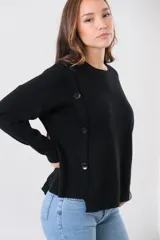 Sweater negro de punto con cuello redondo y corte recto. Presenta detalle de botones grandes en el hombro.
