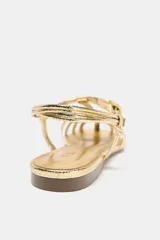 Sandalias planas doradas tipo cangrejeras con tiras finas entrecruzadas y cierre con hebilla ajustable en el tobillo.