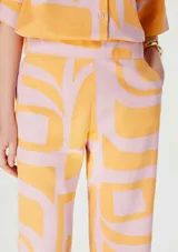 Pantalón capri de lino color rosa con estampado abstracto naranja.