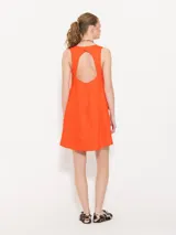 Vestido corto color naranja, sin mangas, con cuello redondo y dos bolsillos frontales con botón.
