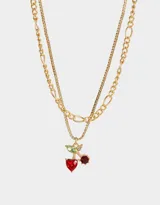 Collar doble con cadenas doradas de diferentes diseños. La cadena más corta tiene dijes de cerezas con strass rojos y verdes. Cierre de mosquetón.