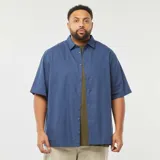 Camisa azul de manga corta con cuello clásico y cierre frontal con botones. Corte holgado.