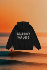 Hoodie negro con capucha y estampado en la espalda con la frase "Glassy Waves" en letras blancas con efecto de llamas.