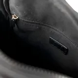 Bandolera negra de poliéster con correa regulable y herrajes plateados. Tiene acceso con cierre, un compartimento principal, un bolsillo interno con cierre, un bolsillo interno abierto y dos bolsillos externos con cierre. El interior está forrado en tela de algodón y poliéster.