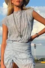Blusa de textura fruncida, con diseño adaptable y sin mangas, confeccionada en acrílico y algodón.