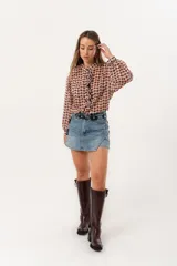 Minifalda de jean azul claro con corte evasé, detalle de short interno y cinturón negro con argollas metálicas.