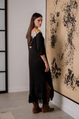 Vestido negro de noche con mangas 3/4, cuello en V con detalles de cuero entrelazado, terminación en flecos y tajos laterales.