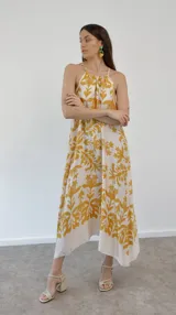 Vestido largo de seda estampada con flores amarillas sobre fondo blanco, corte halter.