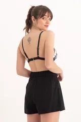 Top de bikini triangular con estampado tropical en tonos verdes y negros sobre fondo blanco. Tiene tirantes finos negros y contorno inferior negro.