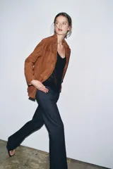 Blazer marrón de ante con cuello de solapa de muescas, manga larga, bolsillos de parche delanteros y cierre frontal con botones.