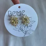 Caravanas doradas con diseño artístico en forma de explosión, adornadas con brillantes.
