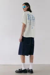 Remera blanca de algodón con cuello redondo y corte holgado. Estampa azul con la palabra 'SYNTHESIS' y texto inferior.