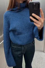 Sweater azul de tejido de punto grueso, con cuello alto y mangas largas acampanadas.