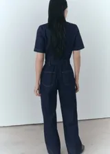 Mono ajustado de mezclilla azul con cierre frontal y cinturón a juego, ideal para un look moderno.