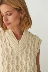 Chaleco de punto color crema con diseño trenzado y cuello en V.