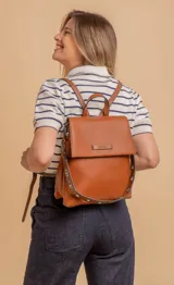 Mochila color verde oliva, tipo cartera, con tapa y doble cierre. Tiene dos compartimentos y división interna, además de un bolsillo trasero con cierre.