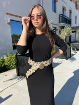 Vestido negro de corte midi, con mangas largas ajustadas y cuello redondo. Incluye cinturón ancho con apliques circulares.