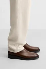 Bota Chelsea marrón de cuero, con elásticos laterales y tirador trasero. Suela negra con ligero tacón.